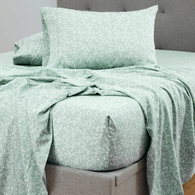 Green patterned sheet set laid out on a bed with matching pillowcases.