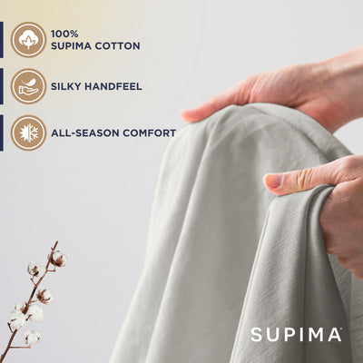 Hands holding a light gray sheet, with a cotton branch visible in the foreground.