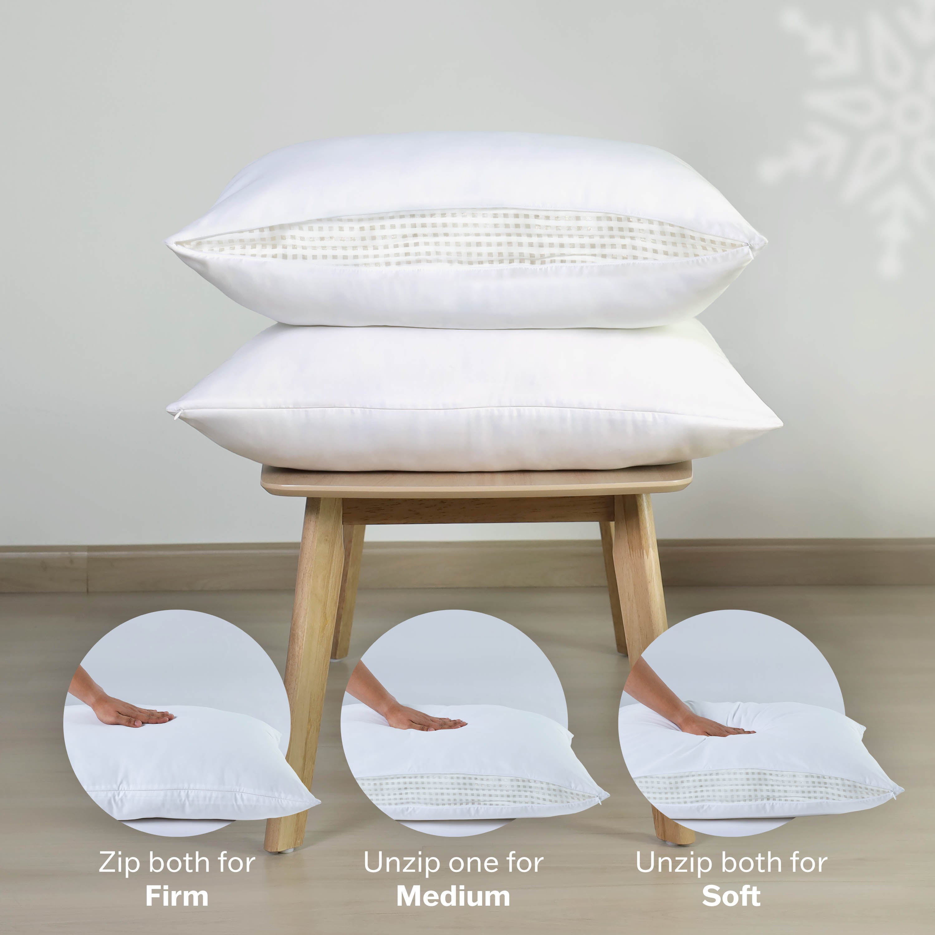Two white blown bed pillows stacked on a wooden stool, with zipper options for firmness adjustments.