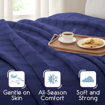 Navy blue cotton blanket draped over a bed with a tray holding a cup of coffee and cookies.