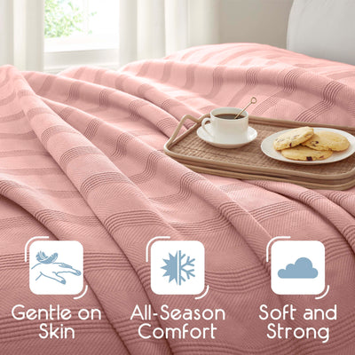 Light pink cotton blanket draped over a bed with a tray holding a cup of coffee and cookies.
