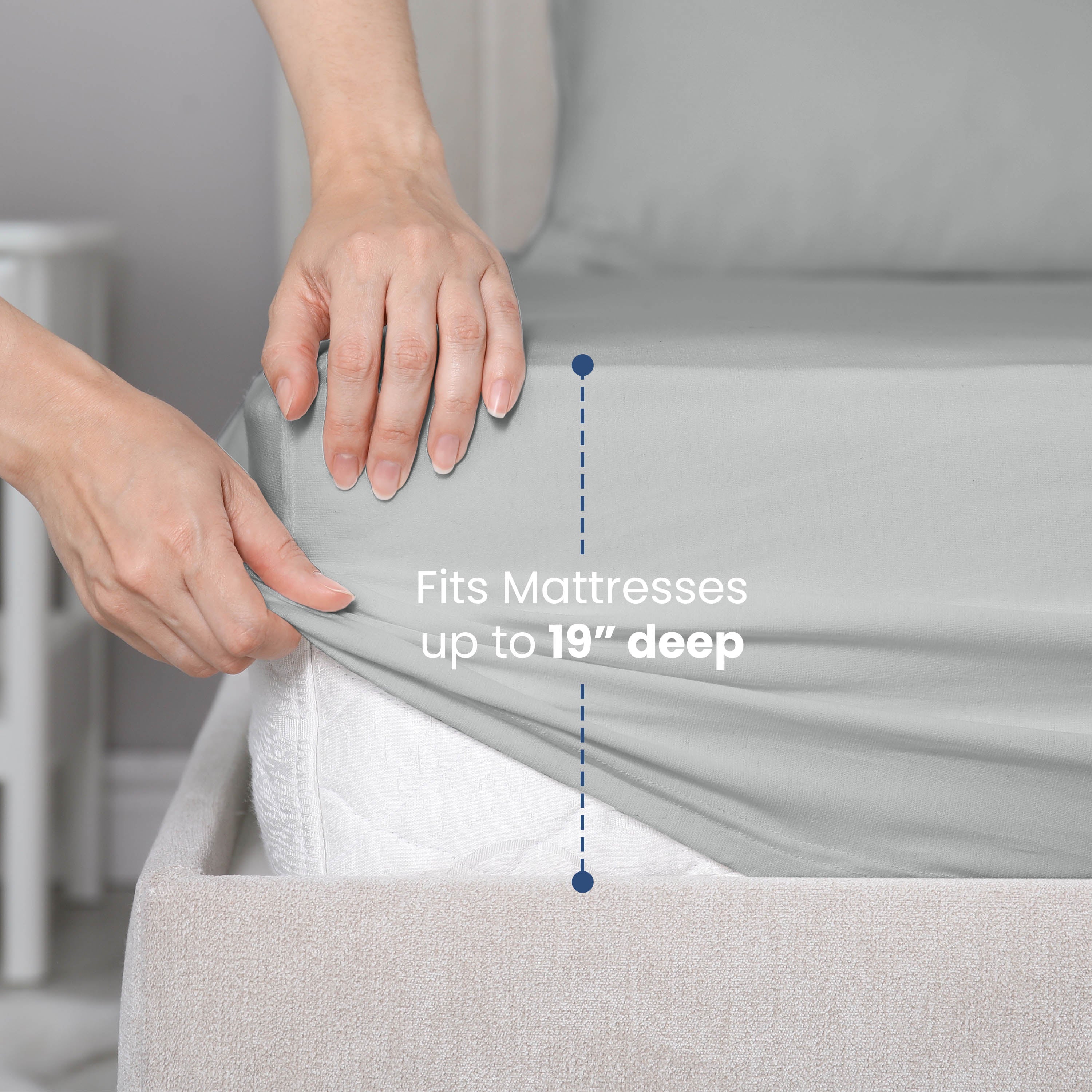 Hands adjusting a fitted gray sheet on a mattress, with text indicating it fits mattresses up to 19 inches deep.