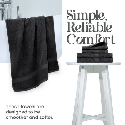 Black towels hanging over a white tub, with a stack of folded towels on a white stool beside them.