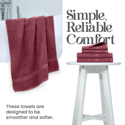 Two burgundy towels hang from a bathtub, with a stack of four folded towels on a white stool nearby.