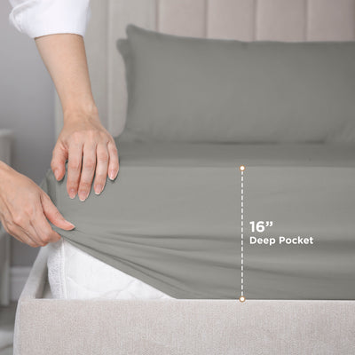 Hand adjusting a gray fitted sheet on a mattress, showing a 16-inch deep pocket feature.