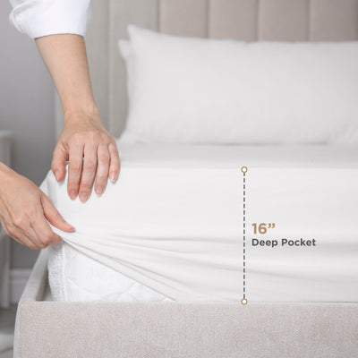 Hand adjusting a white fitted sheet on a mattress, with a label indicating a 16-inch deep pocket.