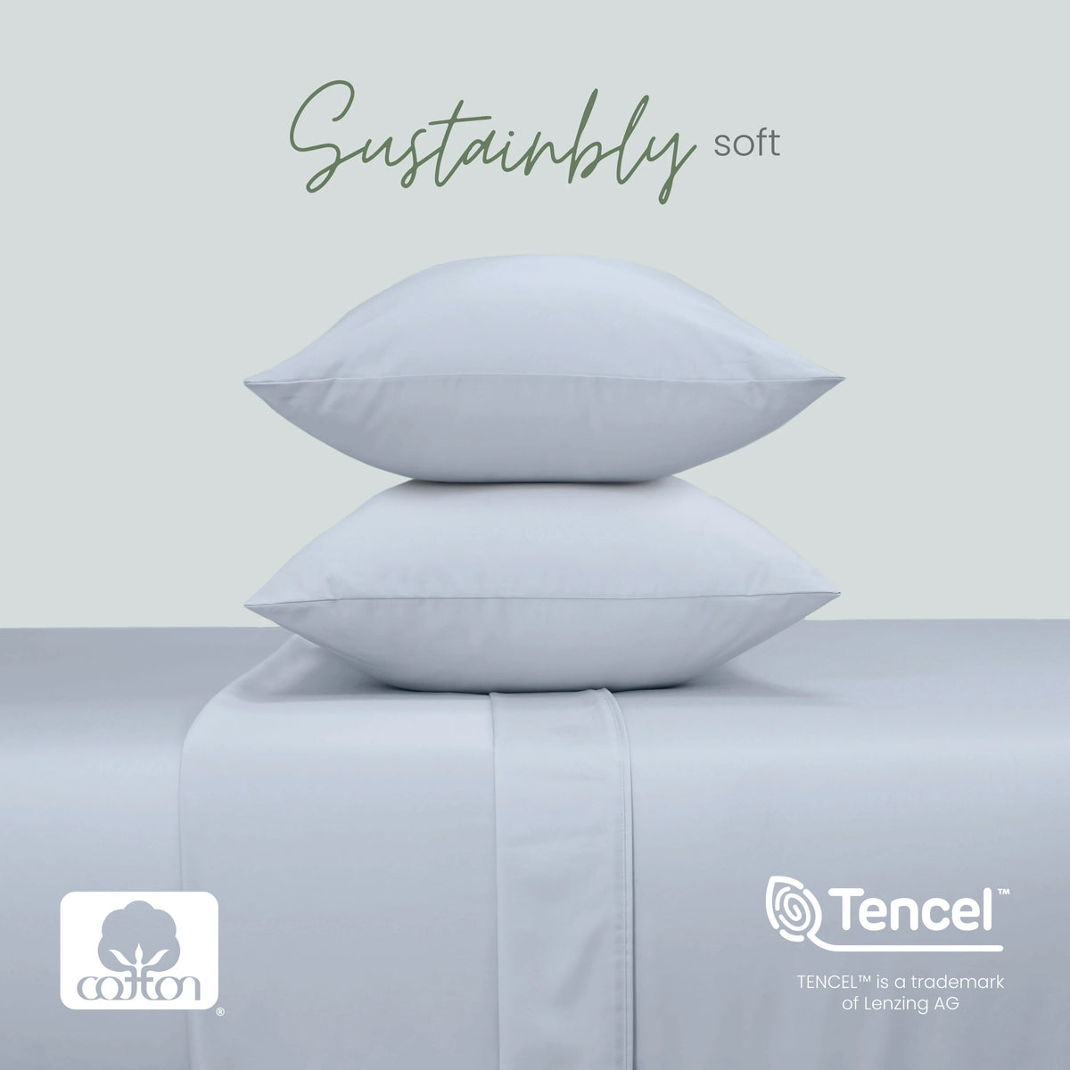 Two blue pillows stacked on a matching upholstered surface, with the words 'Sustainably soft' above. Cotton and Tencel logos appear at the bottom, with a pale gray background.