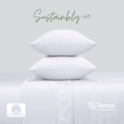 Two white pillows stacked on a matching upholstered surface, with the words 'Sustainably soft' above. Cotton and Tencel logos appear at the bottom, with a pale gray background.
