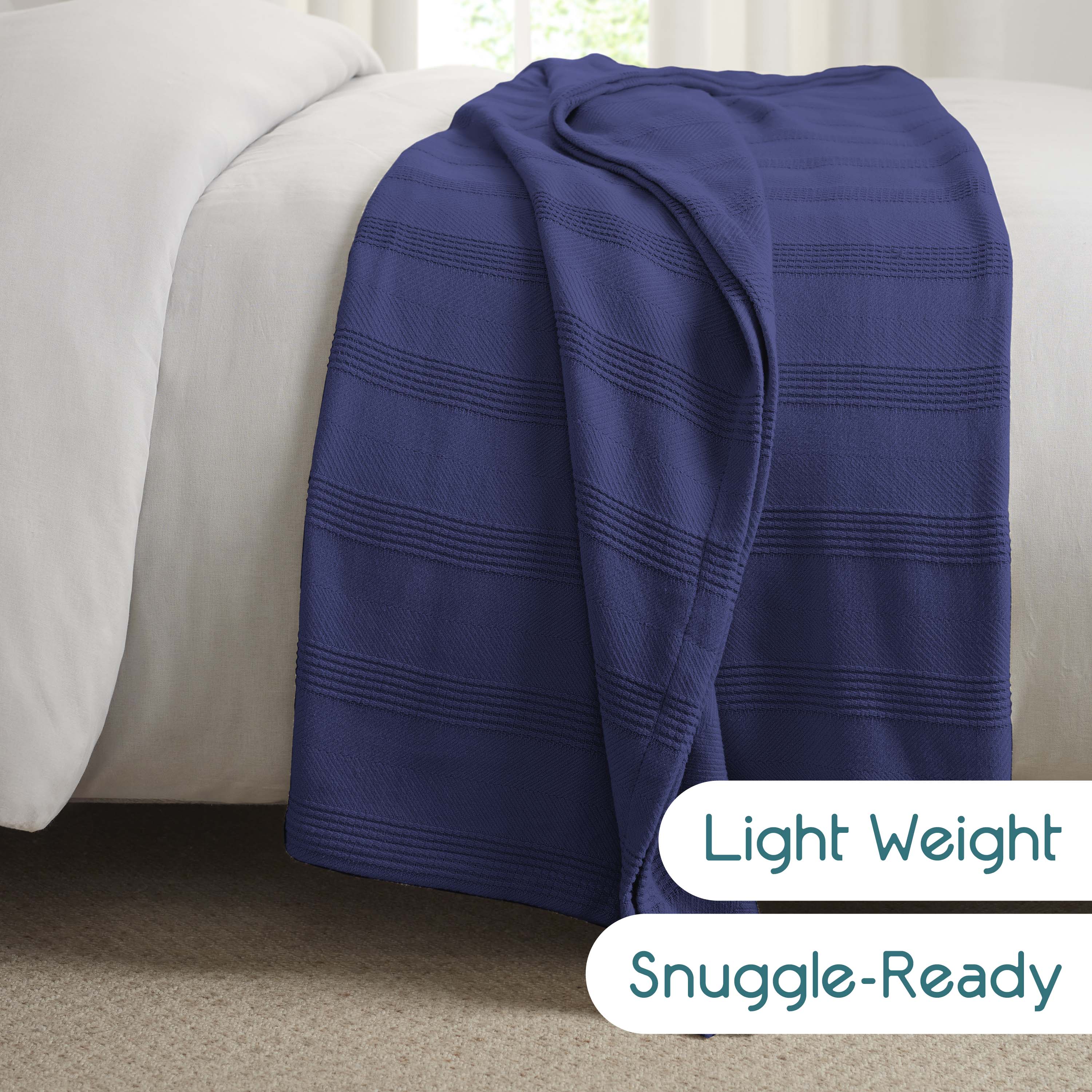 Navy blue cotton blanket draped over a light-colored bedspread with a textured stripe pattern.