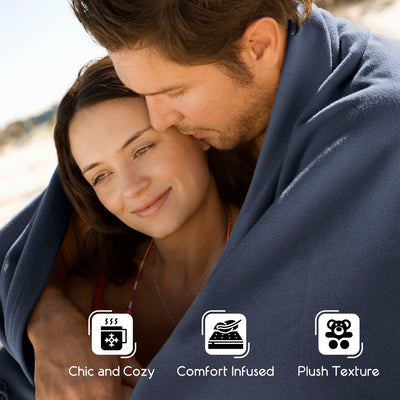 A couple embraces under a soft, dark blanket, with a beach setting in the background.