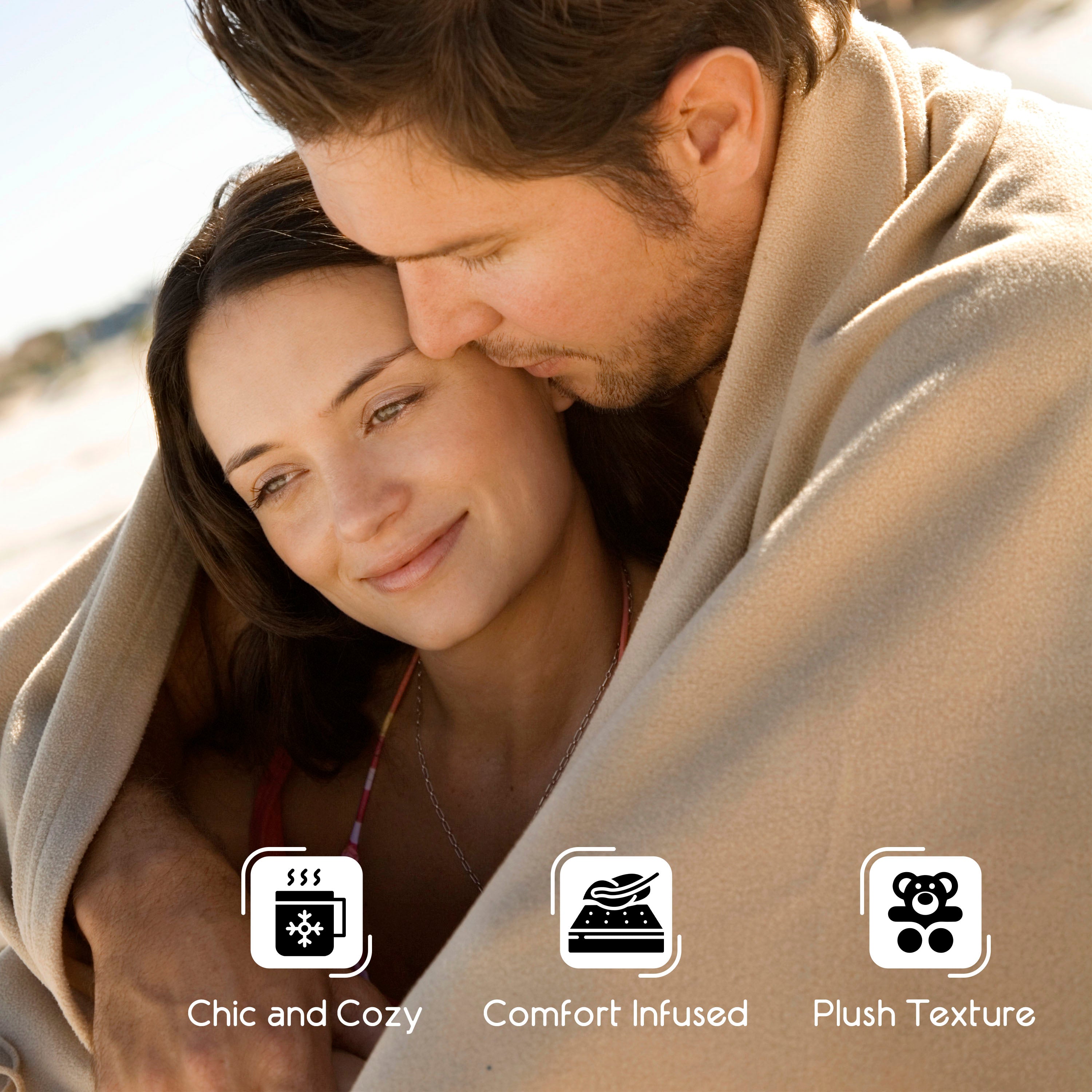 Couple wrapped in a beige blanket, smiling and enjoying each other's company outdoors.