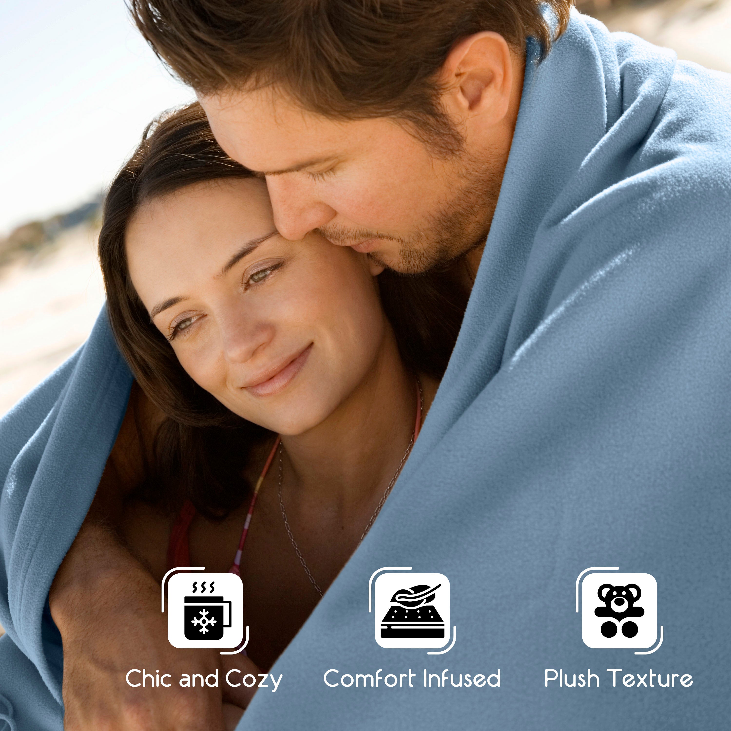 Couple wrapped in a light blue blanket, smiling and enjoying each other's company outdoors.