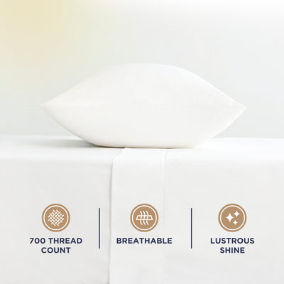 White pillow on a white sheet with icons indicating 700 thread count, breathability, and lustrous shine.