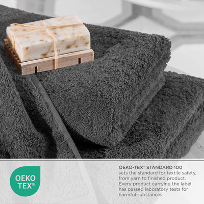 Dark gray towels stacked with a bar of soap on a wooden soap dish, featuring an Oeko-Tex certification label.