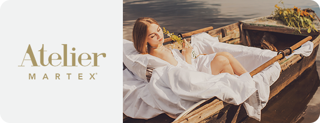 Woman in a white dress lying on a wooden boat with 'Atelier Martex' branding.