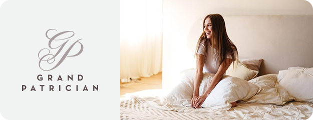 Woman sitting on a bed with 'Grand Patrician' branding on the left.