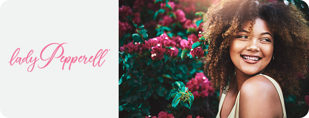 Woman with curly hair smiling outdoors with 'ladyPepperell' branding.