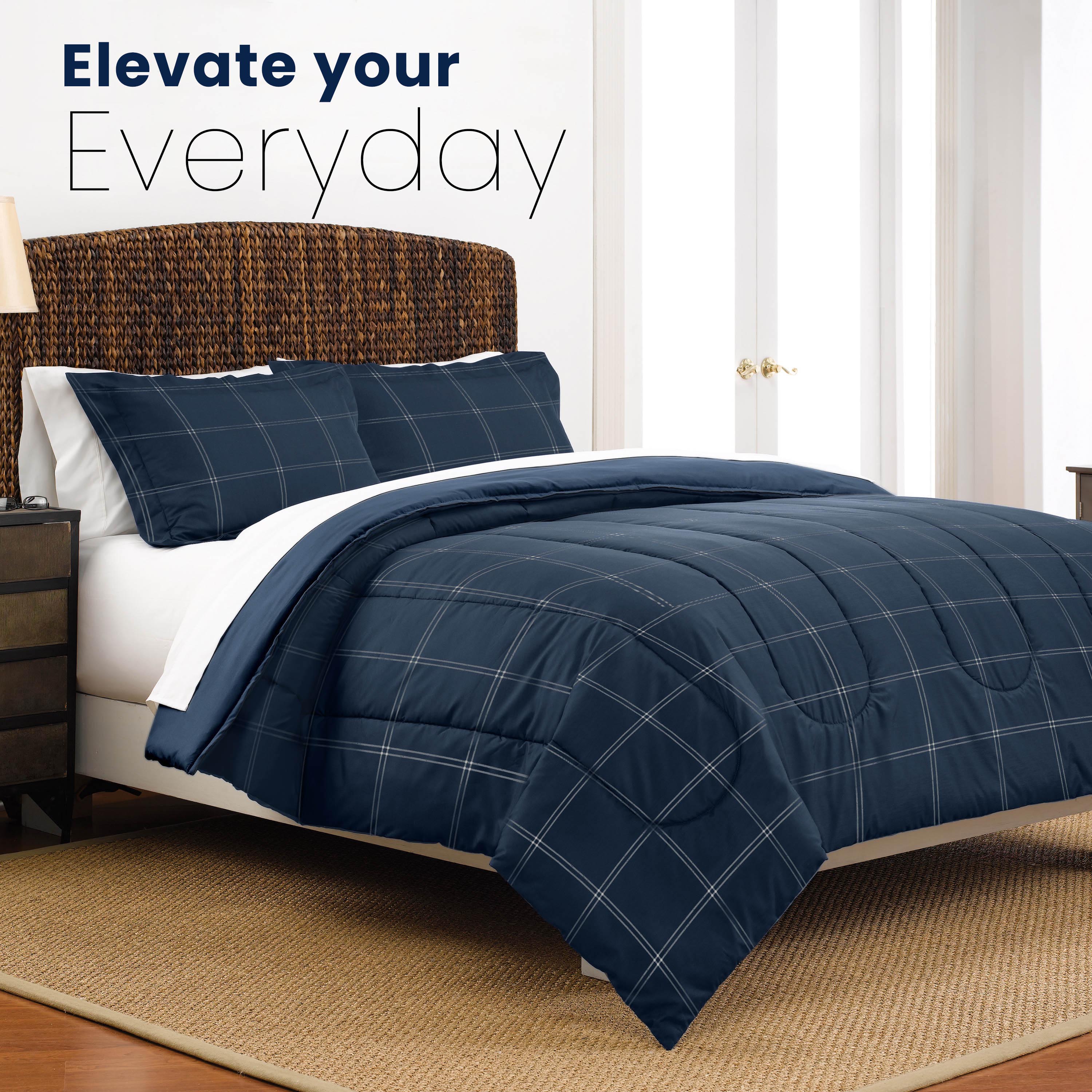Reversible comforter set in navy with a grid pattern, paired with matching pillow shams on a bed.