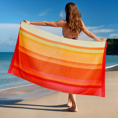 Woman holding a colorful striped towel on a beach