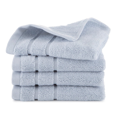 Four stacked light blue wash cloths with a textured surface.
