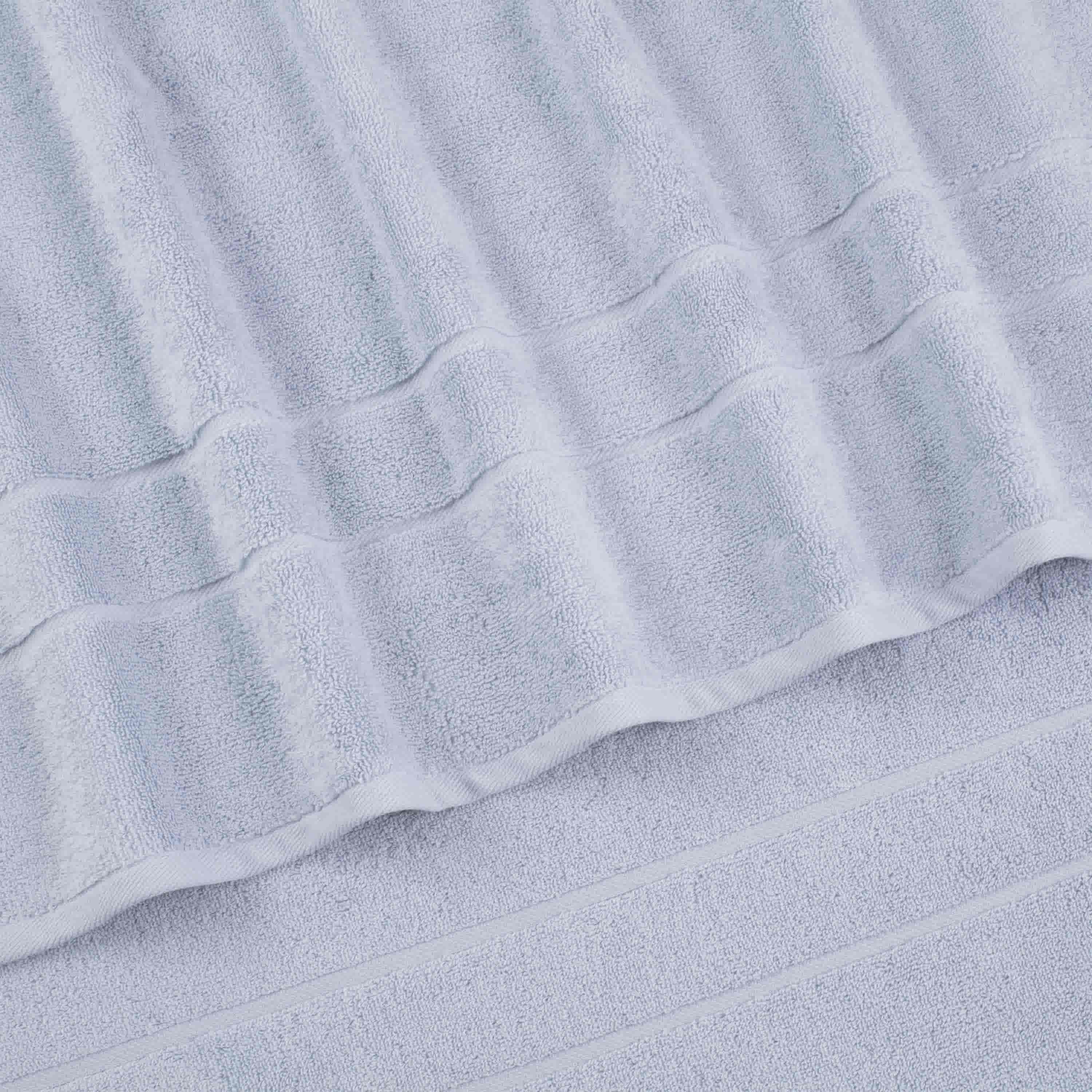Light gray bath towels with textured stripes and a smooth border, arranged in a layered position.