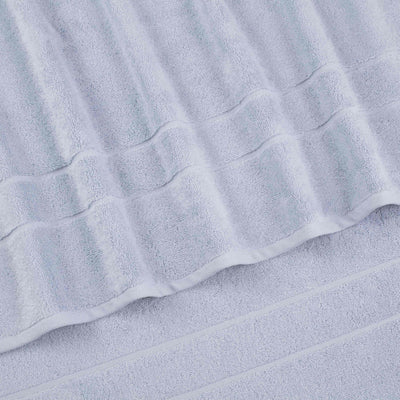 Light gray bath towels with textured stripes and a smooth border, arranged in a layered position.