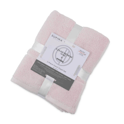 Two soft pink hand towels neatly stacked and wrapped with a label detailing product information.