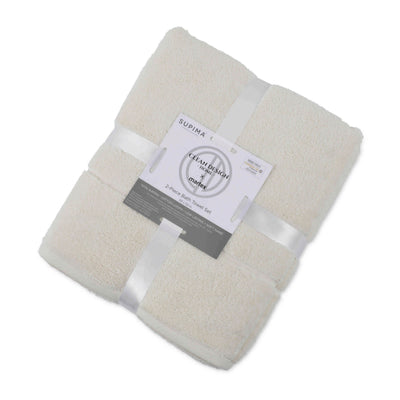 Two folded bath towels in a light beige color, secured with a ribbon and a label detailing the product.