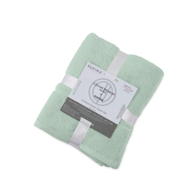 Two mint green hand towels stacked and wrapped with a white ribbon and label detailing product information.