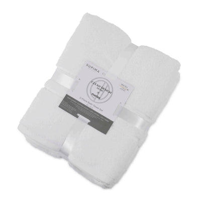 Two white bath towels neatly stacked and tied with a ribbon, featuring a label with product details.