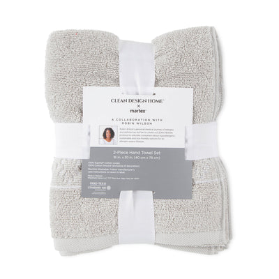 Two-piece hand towel set in light gray, featuring a decorative band and a label with care instructions.