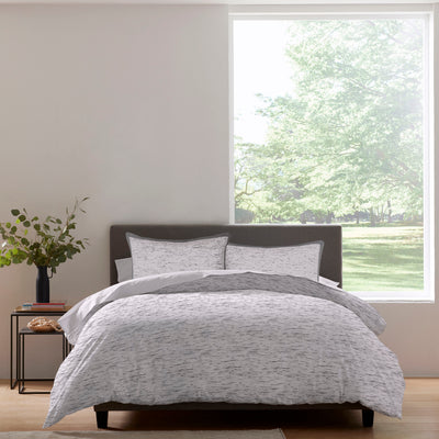 Comforter set featuring a gray and white speckled pattern, paired with matching pillow shams on a bed.