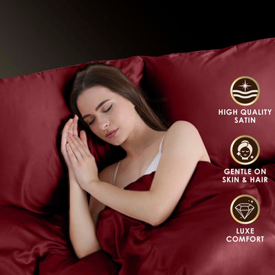 A person is peacefully sleeping on a burgundy satin sheet set with a pillow, surrounded by soft fabric.