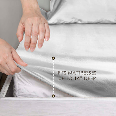 Hands adjusting a satin sheet on a mattress, with text indicating it fits mattresses up to 14 inches deep.