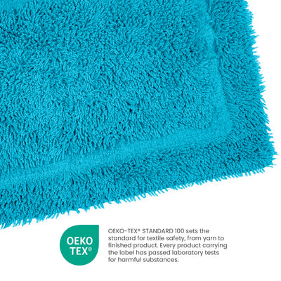 Turquoise ringspun cotton bath rug with a textured surface and a bordered edge.