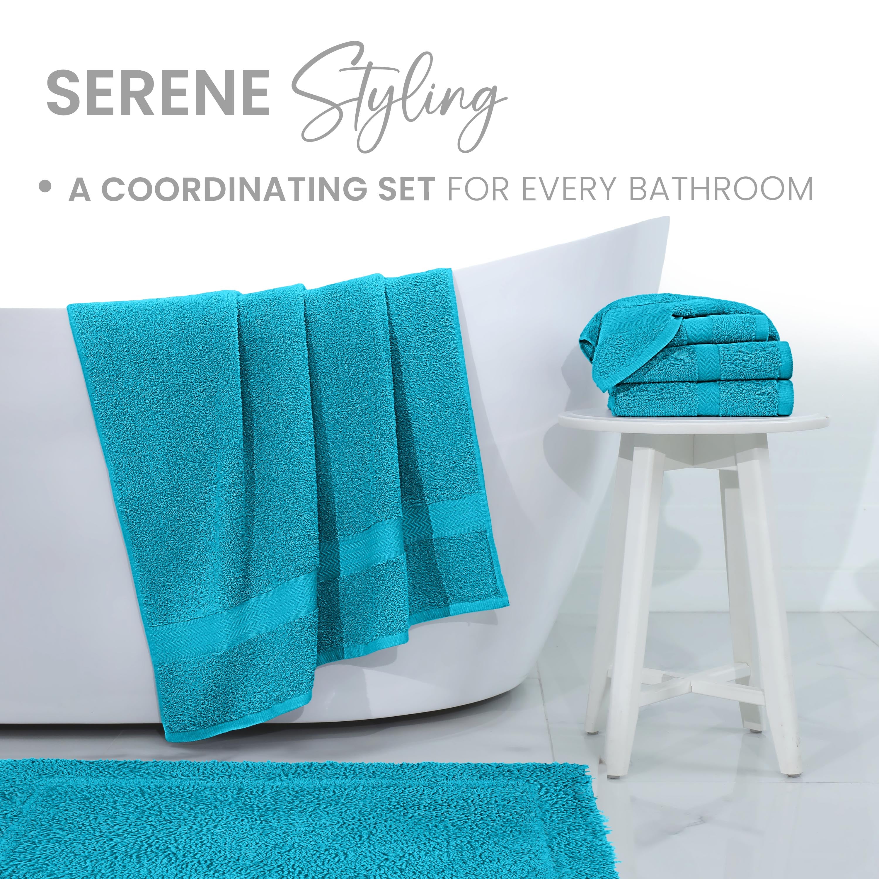 Turquoise bath towels and rug displayed near a white bathtub and a small white stool.