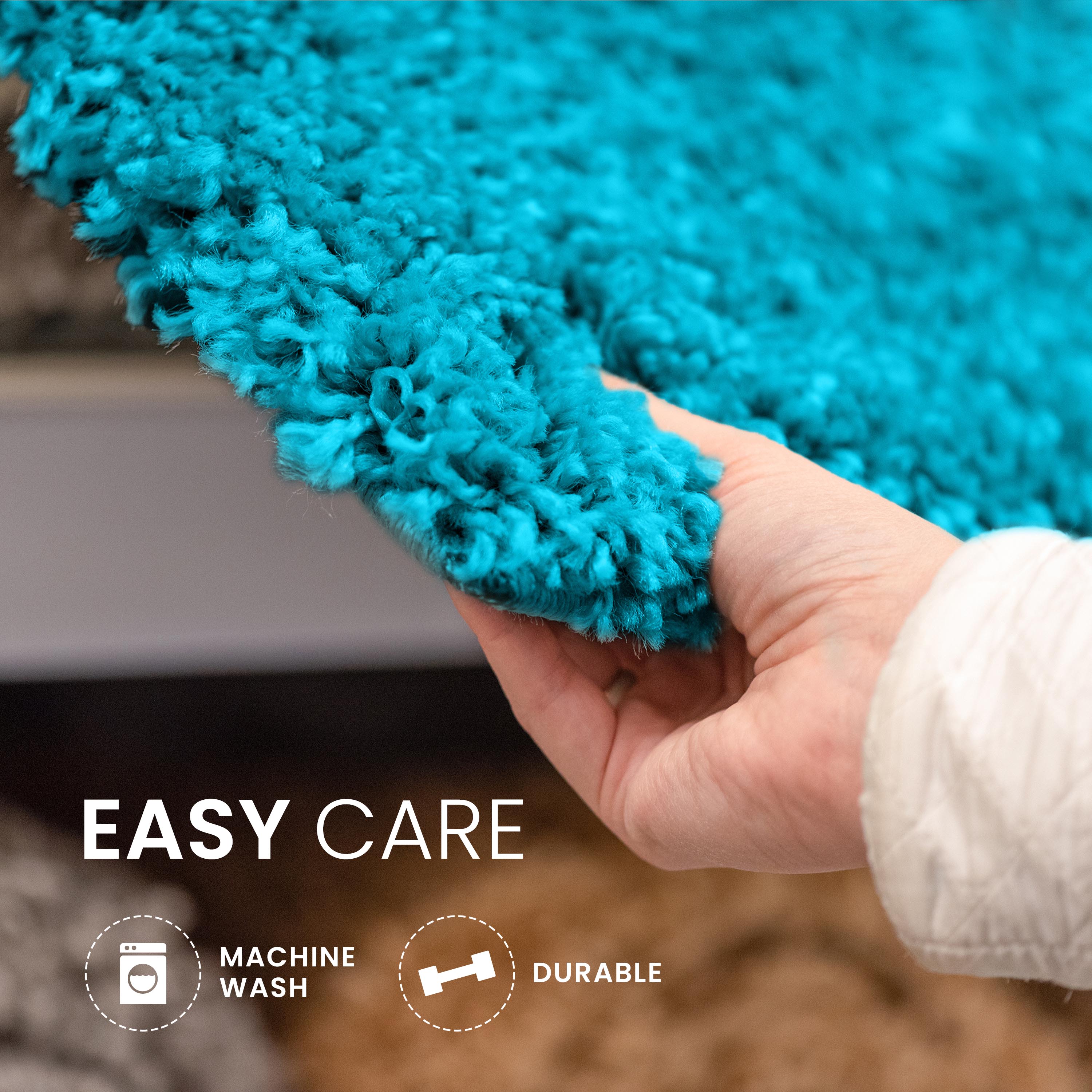 A hand holds a textured, turquoise bath rug with a soft, plush surface.