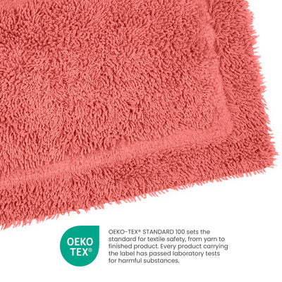 Coral-colored ringspun cotton bath rug with a textured surface and a bordered edge.
