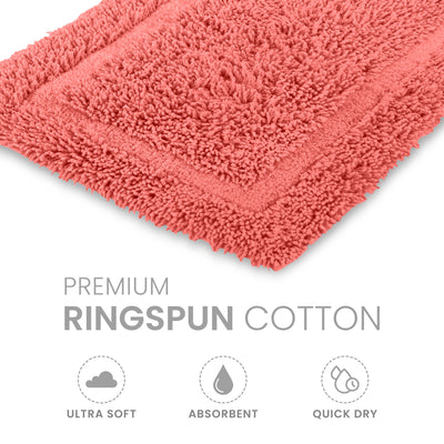 Coral bath rug made of ringspun cotton with a textured surface and bordered design.