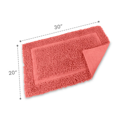 Rectangular bath rug in coral color, measuring 30 inches by 20 inches, with a textured surface and a folded corner.