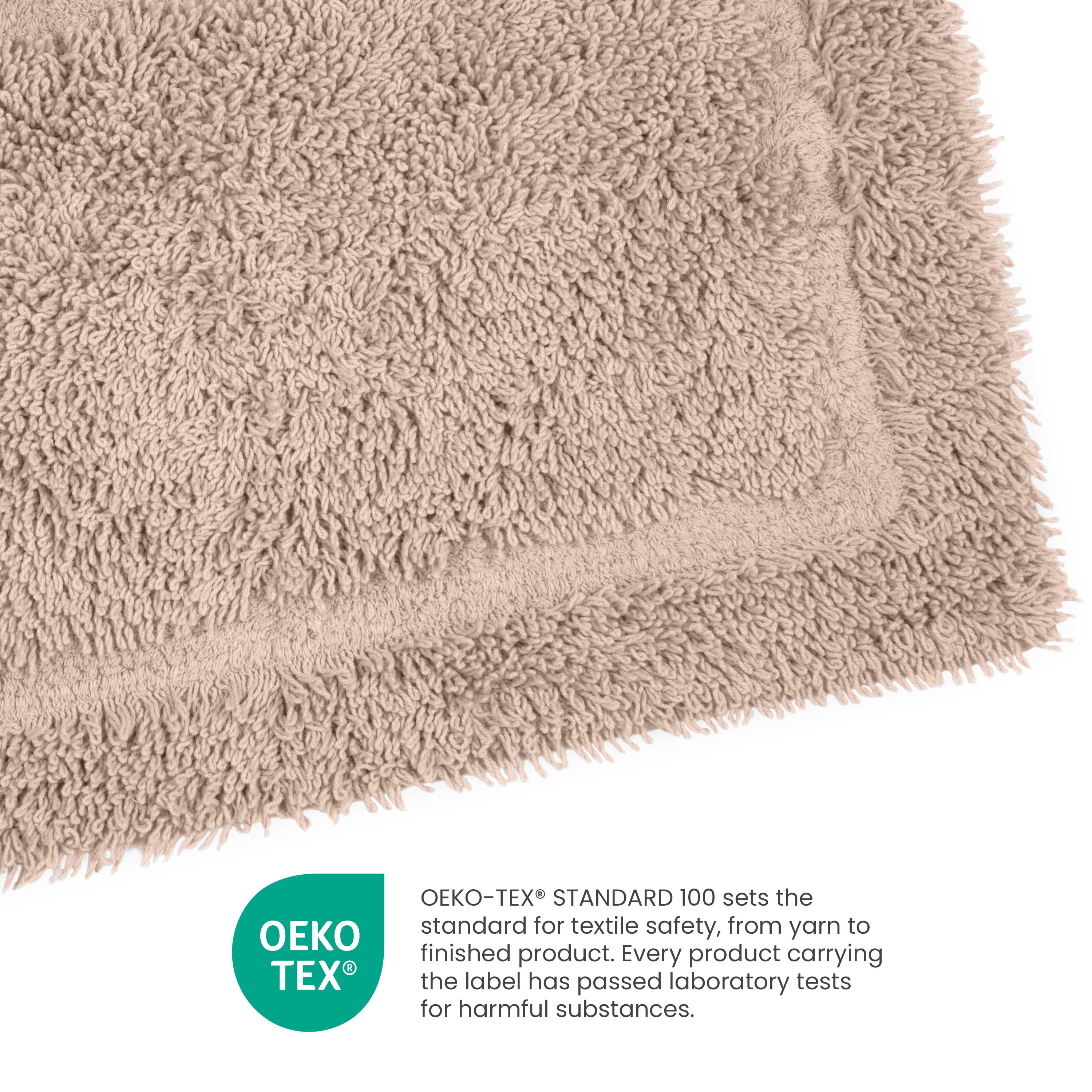 Beige ringspun cotton bath rug with a textured surface and a bordered edge.
