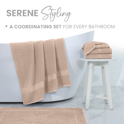 Soft beige bath rug displayed in a bathroom setting with towels hanging and stacked on a stool.