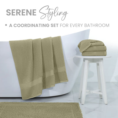 Soft, light green bath rug with matching towels draped over a white bathtub and stacked on a small white stool.
