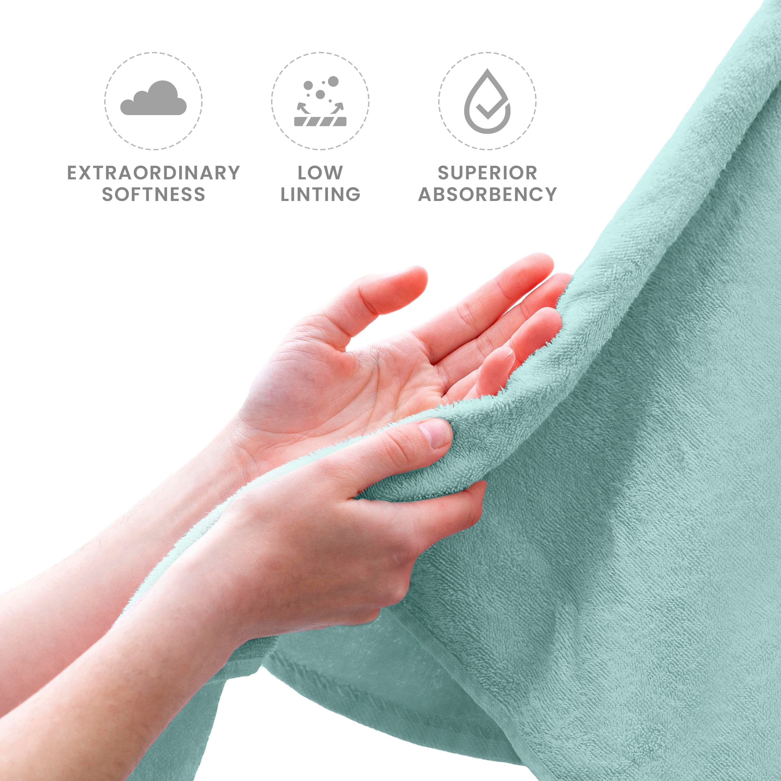 Hands holding a soft, mint green towel with a focus on its texture and quality.