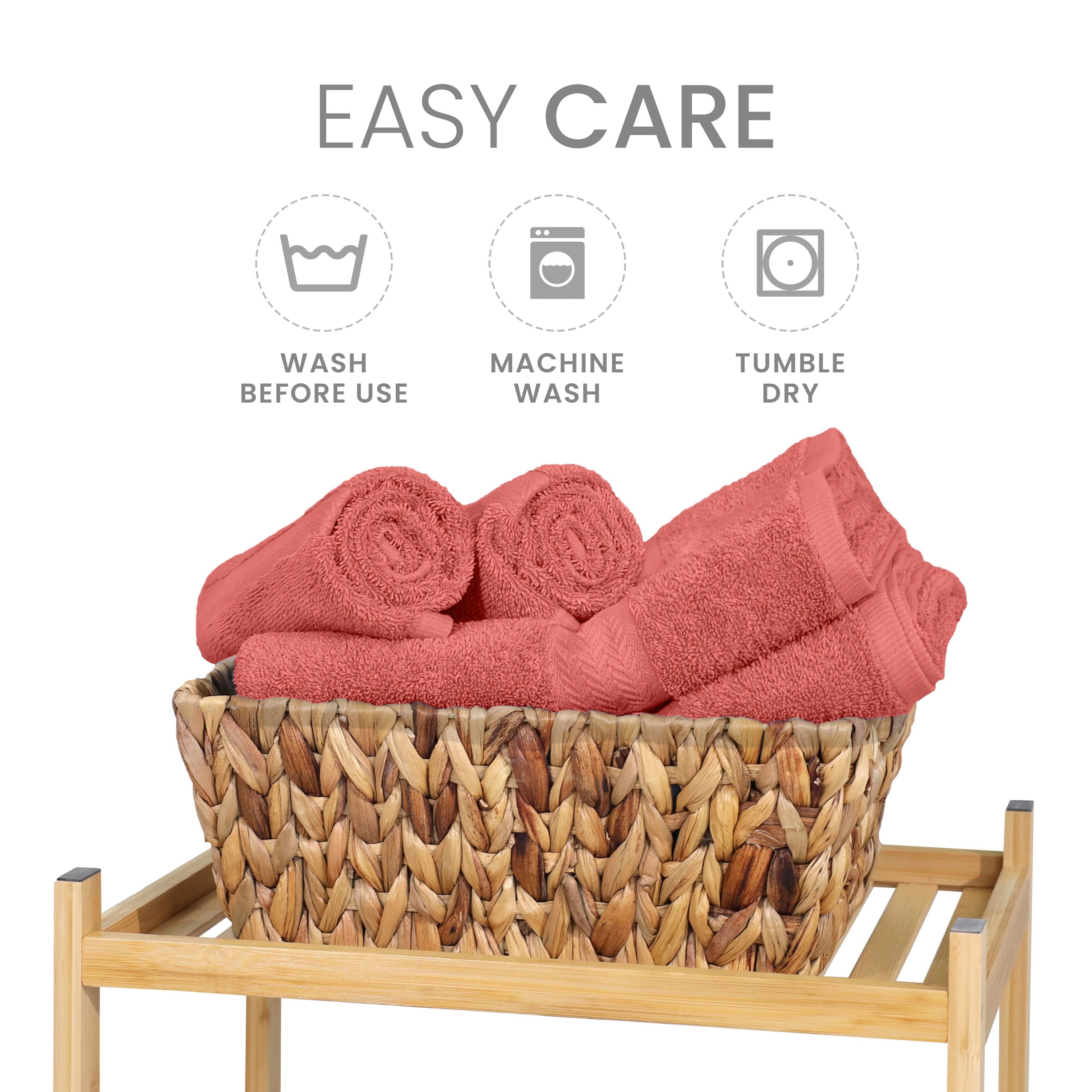 Six coral towels are neatly arranged in a woven basket on a wooden stand, with care instructions displayed above.