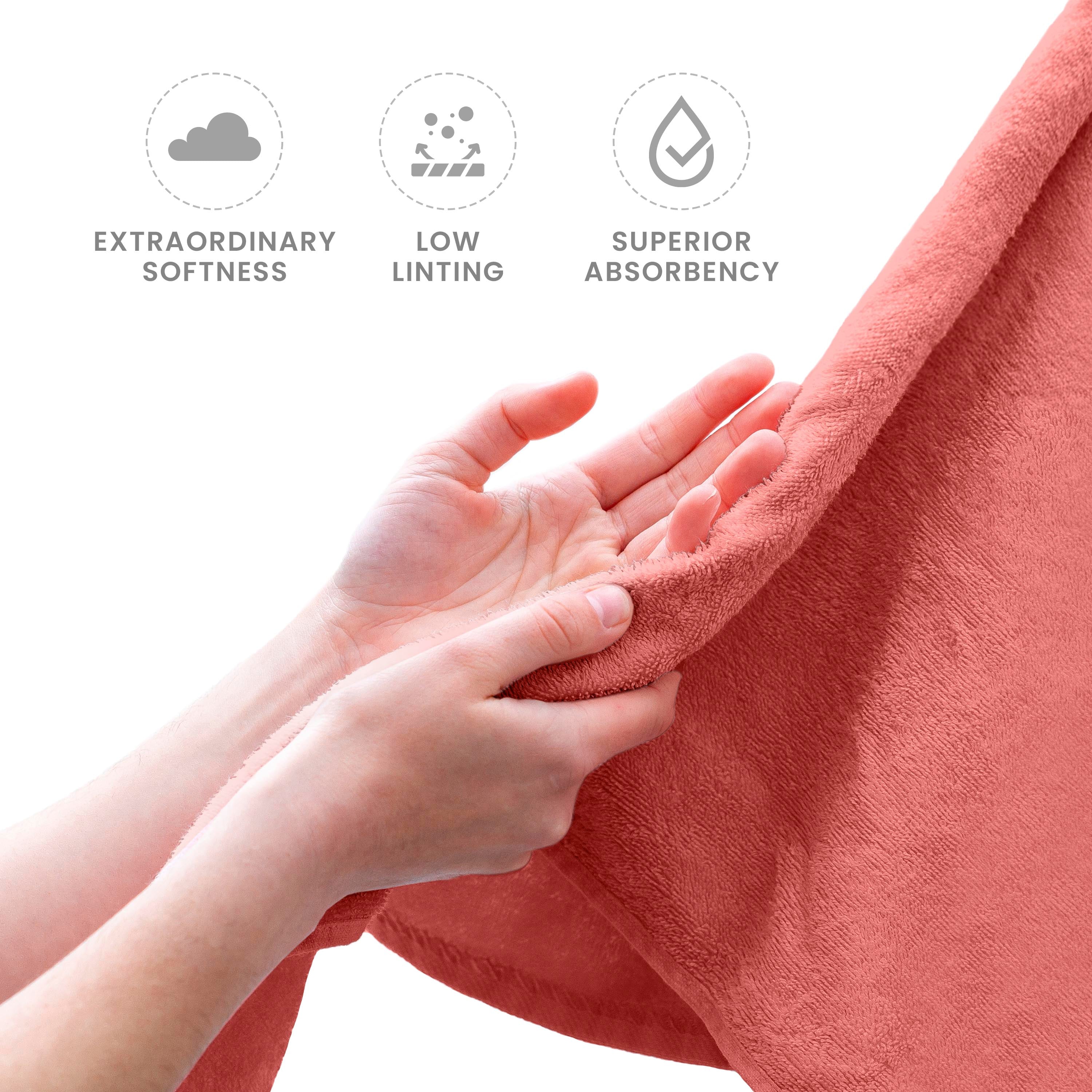 Hands holding a soft, coral-colored towel, showcasing its texture and quality.