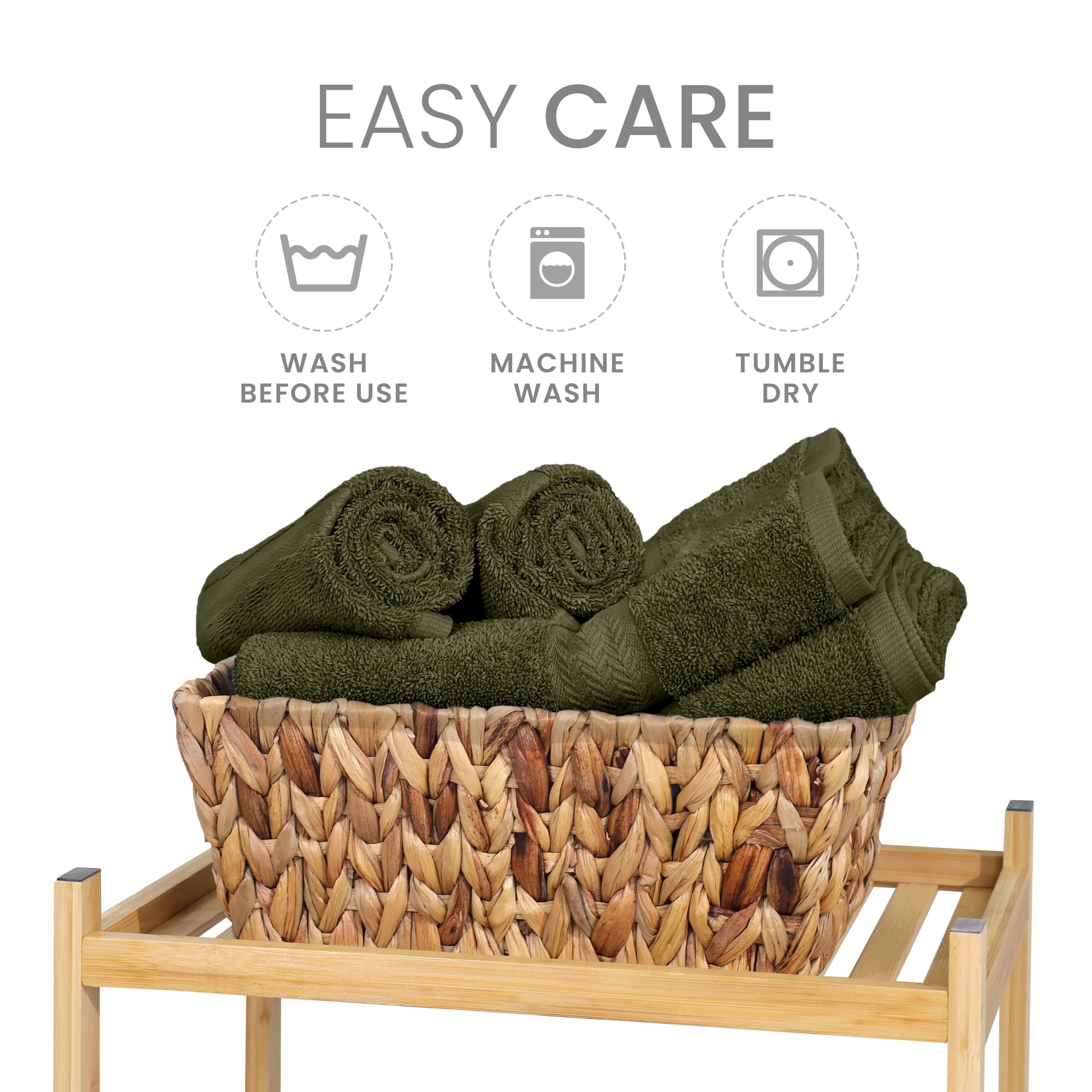 Set of green towels neatly rolled and stacked in a woven basket on a wooden stand, with care instructions displayed above.