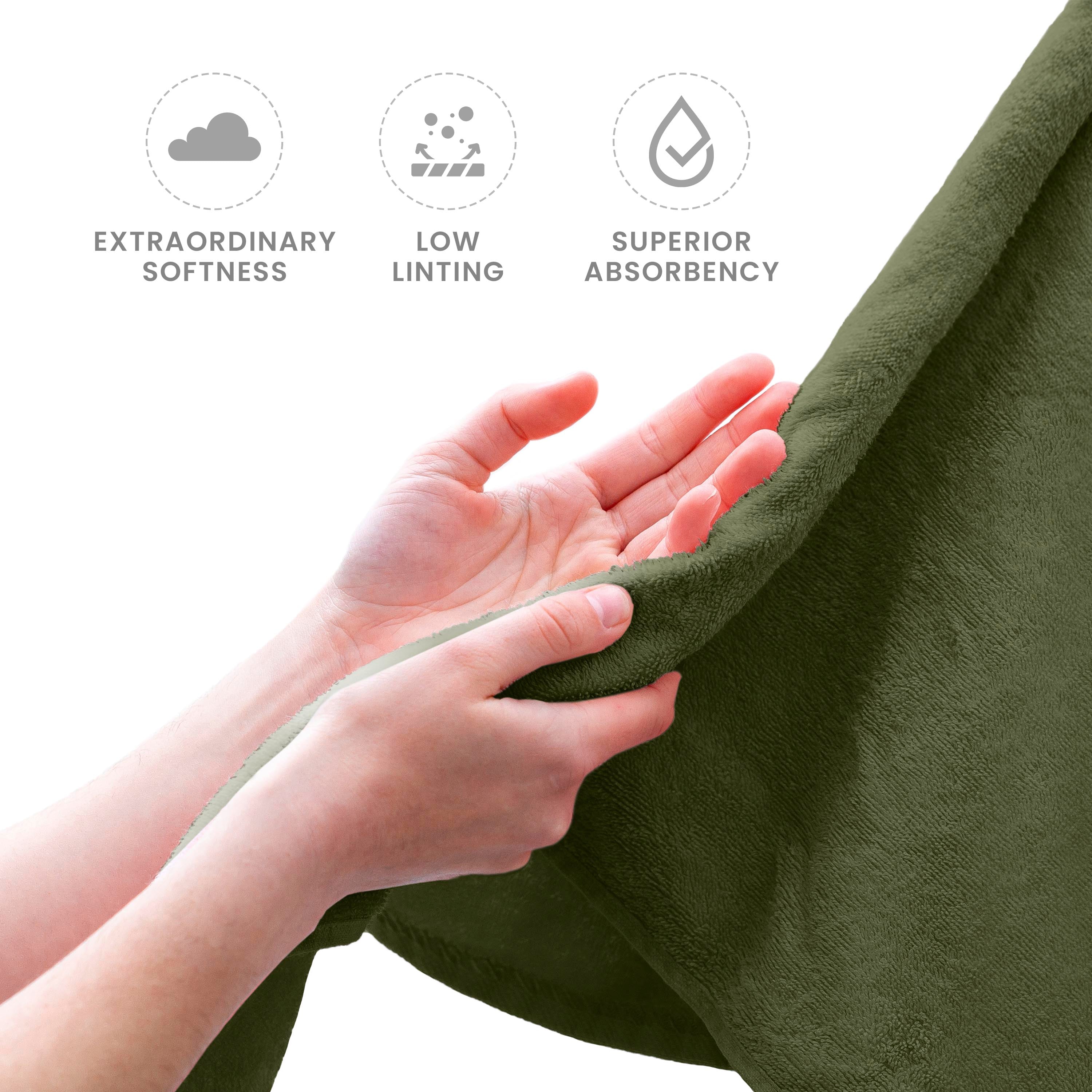 Hands holding a soft, green towel with a textured surface.