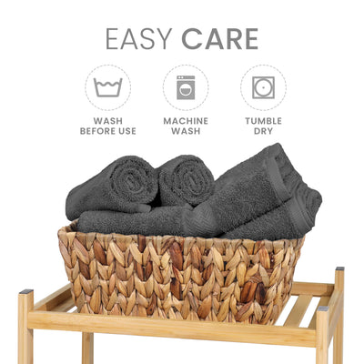 Gray towels neatly rolled and stacked in a woven basket on a wooden shelf, with care instructions displayed above.
