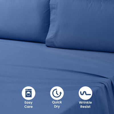 Solid blue sheet set with two matching pillowcases on a bed surface.
